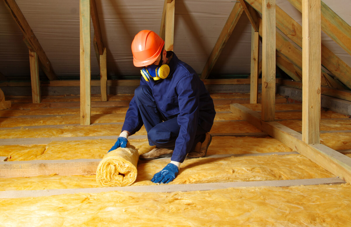 Worker insulates an attic with mineral wool.