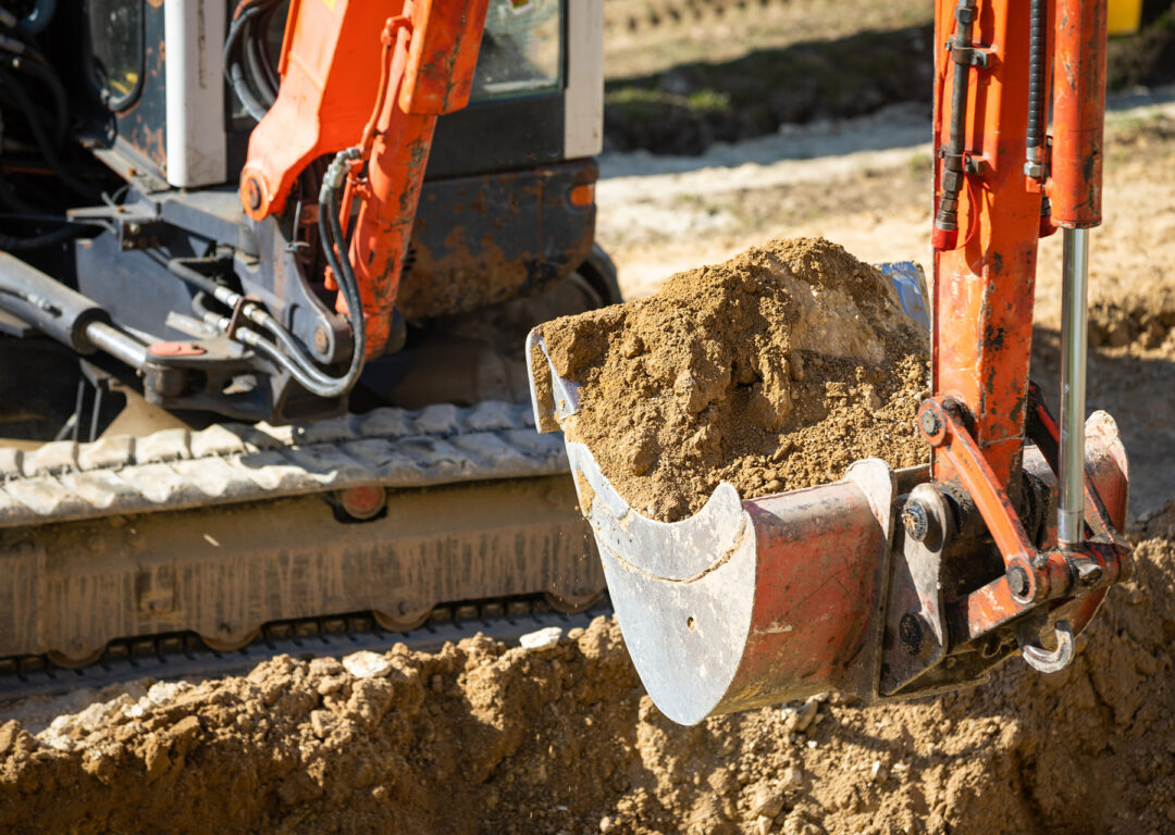 Close-up of excavator working with soil on construction site.